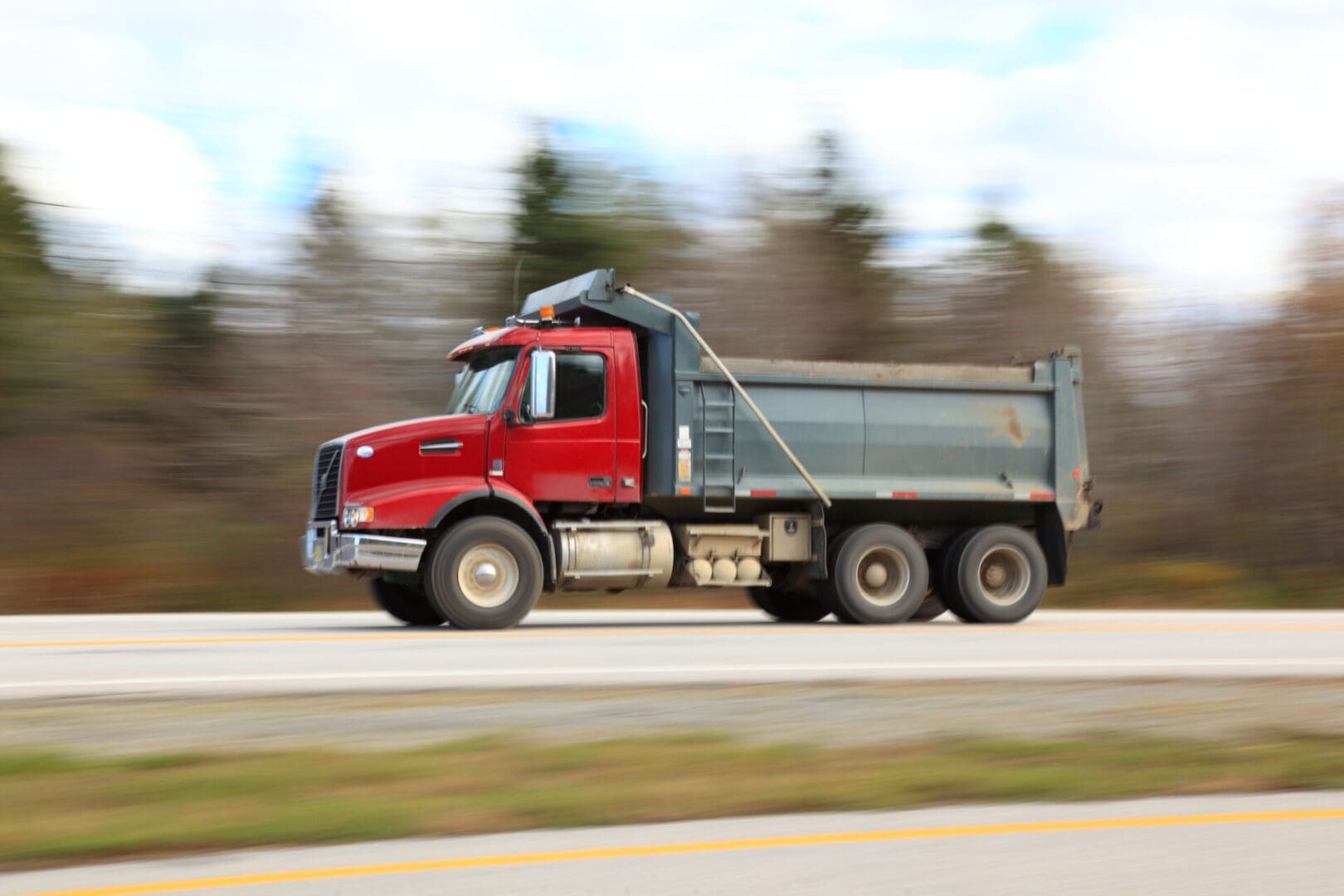 Red dump truck speeding down highway