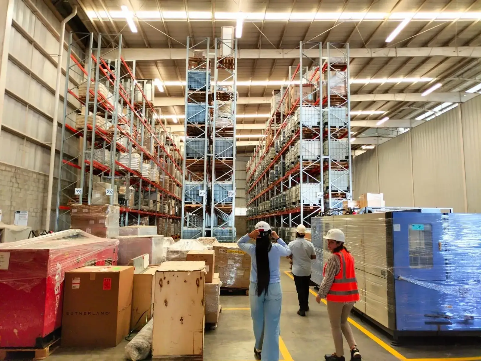 Workers walking through large warehouse pallet racks